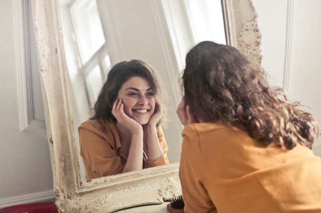 Usmiata žena pozerajúca sa do zrkadla